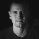 Black and white portrait of a pensive man looking directly at the camera.